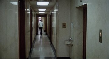 Movie still from “The In-Laws” (1979), directed by Arthur Hiller – A person walking down a hallway in an office building; Extreme Wide shot, High angle