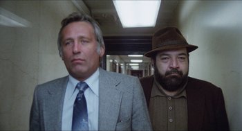 Movie still from “The In-Laws” (1979), directed by Arthur Hiller – Two men standing next to each other in a hallway; Medium shot, Low angle