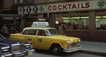 Movie still from “The In-Laws” (1979), directed by Arthur Hiller – A yellow taxi cab driving down the street; Wide shot, Low angle