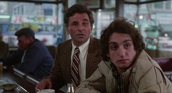 Movie still from “The In-Laws” (1979), directed by Arthur Hiller – Two men sitting at a table with a cup of coffee; Medium shot, Over the shoulder angle