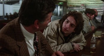 Movie still from “The In-Laws” (1979), directed by Arthur Hiller – Two men sitting at a table talking to each other; Medium shot, Over the shoulder angle