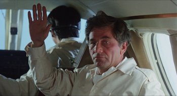 Movie still from “The In-Laws” (1979), directed by Arthur Hiller – A man waves while sitting in the back seat of a car; Close Up shot, Low angle