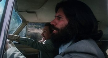 Movie still from “The In-Laws” (1979), directed by Arthur Hiller – A man with a beard is driving in a car; Close Up shot, Low angle