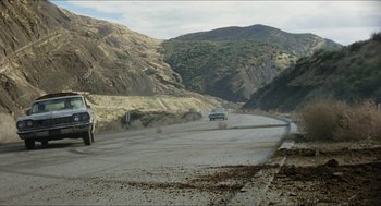 Movie still from “The In-Laws” (1979), directed by Arthur Hiller – Cars driving down a road in the middle of the desert; Extreme Wide shot, High angle