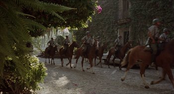 Movie still from “The In-Laws” (1979), directed by Arthur Hiller – A group of men riding horses down a street; Extreme Wide shot, Low angle