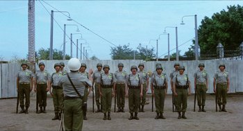 Movie still from “The In-Laws” (1979), directed by Arthur Hiller – A group of men standing in front of each other; Wide shot, Low angle
