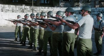 Movie still from “The In-Laws” (1979), directed by Arthur Hiller – A group of men standing next to each other holding guns; Wide shot, High angle