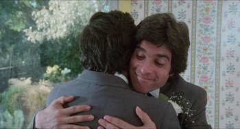 Movie still from “The In-Laws” (1979), directed by Arthur Hiller – Two young men hugging each other in a room; Close Up shot, Over the shoulder angle
