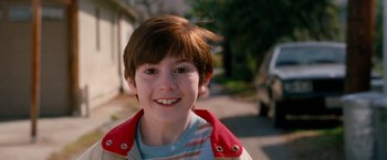 Movie still from “The Incredible Burt Wonderstone” (2013), directed by Don Scardino – A young boy smiling for the camera on the sidewalk; Close Up shot, High angle