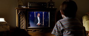 Movie still from “The Incredible Burt Wonderstone” (2013), directed by Don Scardino – A young boy is watching a man on a television screen; Medium shot, Over the shoulder angle