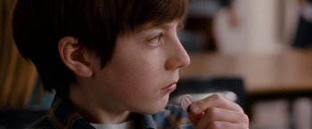Movie still from “The Incredible Burt Wonderstone” (2013), directed by Don Scardino – A young boy holding a piece of food in his hand; Extreme Close Up shot, Over the shoulder angle
