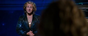 Movie still from “The Incredible Burt Wonderstone” (2013), directed by Don Scardino – A man with long blonde hair wearing a black jacket; Medium shot, Over the shoulder angle
