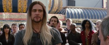 Movie still from “The Incredible Burt Wonderstone” (2013), directed by Don Scardino – A man with long blonde hair standing in front of a group of men; Close Up shot, Over the shoulder angle