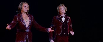 Movie still from “The Incredible Burt Wonderstone” (2013), directed by Don Scardino – A man in a red suit is holding his hand out to another man in a red suit; Medium shot, Low angle