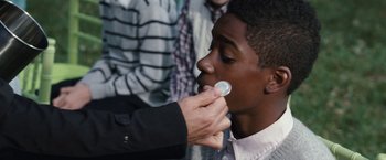 Movie still from “The Incredible Burt Wonderstone” (2013), directed by Don Scardino – A man is putting a condom on a boy's face; Close Up shot, Over the shoulder angle