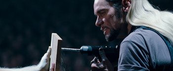 Movie still from “The Incredible Burt Wonderstone” (2013), directed by Don Scardino – A man using a power drill on a piece of wood; Close Up shot, Over the shoulder angle