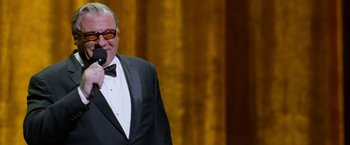 Movie still from “The Incredible Burt Wonderstone” (2013), directed by Don Scardino – A man in a suit and bow tie holding a microphone; Medium shot, Over the shoulder angle