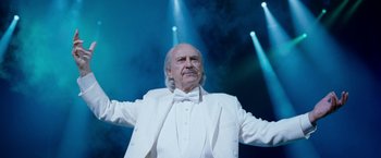 Movie still from “The Incredible Burt Wonderstone” (2013), directed by Don Scardino – An older man in a white suit and bow tie; Medium shot, Low angle