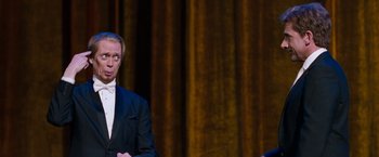 Movie still from “The Incredible Burt Wonderstone” (2013), directed by Don Scardino – A man standing in front of an audience wearing a suit and tie; Medium shot, Over the shoulder angle