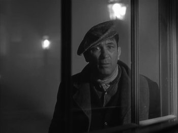 Movie still from “The Informer” (1935), directed by John Ford – A black and white photo of a man looking out of a window; Close Up shot, Low angle