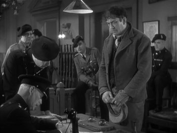 Movie still from “The Informer” (1935), directed by John Ford – A group of men standing next to each other in a room; Medium shot, Low angle