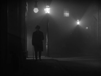 Movie still from “The Informer” (1935), directed by John Ford – A man standing in the dark with a cane; Wide shot, Low angle