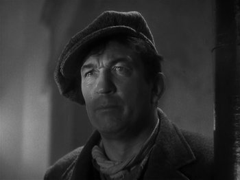 Movie still from “The Informer” (1935), directed by John Ford – A man wearing a hat and a jacket; Close Up shot, Low angle