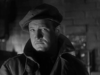 Movie still from “The Informer” (1935), directed by John Ford – A black and white photo of a man wearing a hat; Close Up shot, Low angle