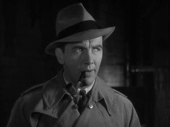 Movie still from “The Informer” (1935), directed by John Ford – A black and white photo of a man smoking a pipe; Close Up shot, Low angle