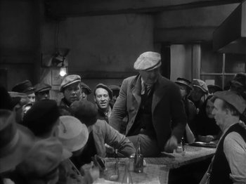 Movie still from “The Informer” (1935), directed by John Ford – A group of men sitting at a table with drinks; Medium shot, High angle