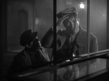 Movie still from “The Informer” (1935), directed by John Ford – Two men looking out of a window at night; Medium shot, Low angle