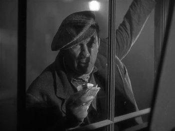 Movie still from “The Informer” (1935), directed by John Ford – A black and white photo of a man looking out of a window; Medium shot, Low angle