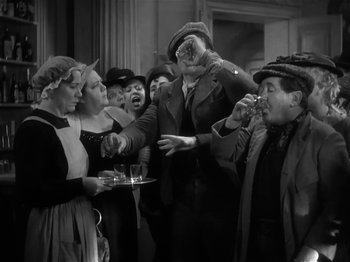 Movie still from “The Informer” (1935), directed by John Ford – A group of people standing around each other in a room; Medium shot, High angle