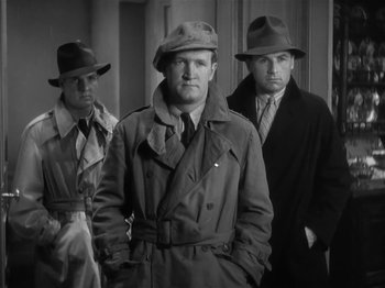 Movie still from “The Informer” (1935), directed by John Ford – A group of men standing next to each other wearing hats; Medium shot, Low angle