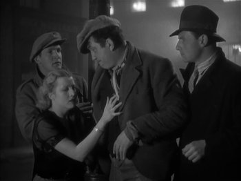 Movie still from “The Informer” (1935), directed by John Ford – A group of people standing around each other in a room; Medium shot, Low angle