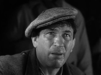 Movie still from “The Informer” (1935), directed by John Ford – A black and white photo of a man wearing a hat; Close Up shot, Low angle
