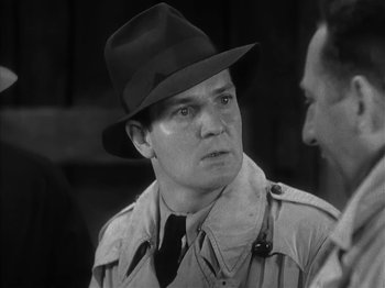 Movie still from “The Informer” (1935), directed by John Ford – A man wearing a hat and a trench coat; Close Up shot, Over the shoulder angle