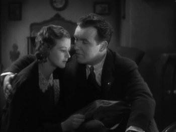 Movie still from “The Informer” (1935), directed by John Ford – A man and a woman sitting on a couch together; Medium shot, Low angle