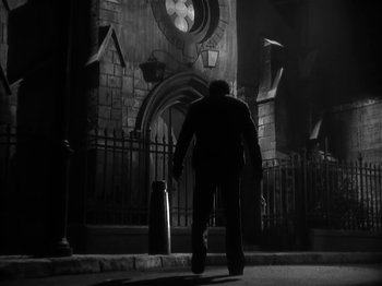 Movie still from “The Informer” (1935), directed by John Ford – A man walking down the street in front of a building; Wide shot, Low angle