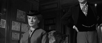 Movie still from “The Innocents” (1961), directed by Jack Clayton – A woman wearing a hat sitting in a chair; Medium shot, Low angle