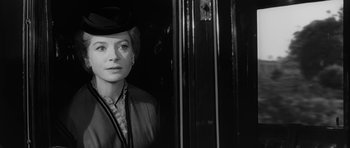 Movie still from “The Innocents” (1961), directed by Jack Clayton – A black and white photo of a woman in a hat; Close Up shot, Over the shoulder angle