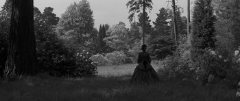 Movie still from “The Innocents” (1961), directed by Jack Clayton – A woman in a long black dress in a field; Extreme Wide shot, Low angle
