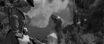 Movie still from “The Innocents” (1961), directed by Jack Clayton – A young girl in a white dress looking at a man in a cowboy hat; Medium shot, High angle