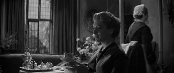 Movie still from “The Innocents” (1961), directed by Jack Clayton – A woman holding a tea cup in front of a table; Medium shot, Low angle
