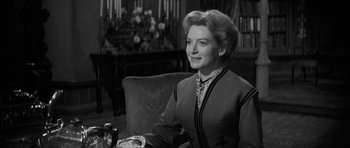 Movie still from “The Innocents” (1961), directed by Jack Clayton – An older woman sitting at a table in a room; Close Up shot, Over the shoulder angle