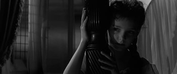 Movie still from “The Innocents” (1961), directed by Jack Clayton – A woman holding a wooden object in front of her face; Close Up shot, High angle