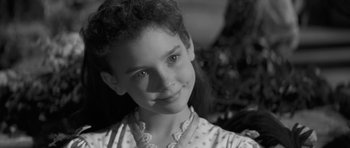 Movie still from “The Innocents” (1961), directed by Jack Clayton – A young girl is smiling for the camera; Close Up shot, Over the shoulder angle