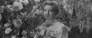 Movie still from “The Innocents” (1961), directed by Jack Clayton – An old black and white photo of a woman holding flowers; Close Up shot, Low angle