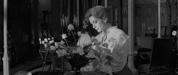 Movie still from “The Innocents” (1961), directed by Jack Clayton – A woman sitting in front of a vase of flowers; Medium shot, Low angle