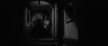 Movie still from “The Innocents” (1961), directed by Jack Clayton – A black and white photo of a woman in a black dress; Wide shot, Low angle